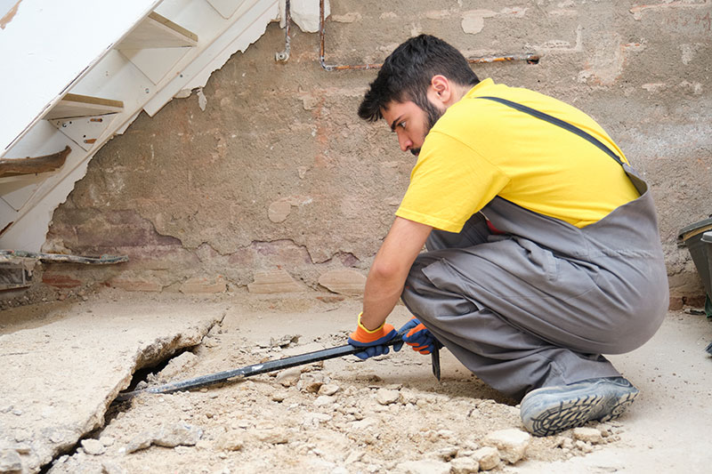 tailored-solutions_man-prepping-basement-floor-for-repair